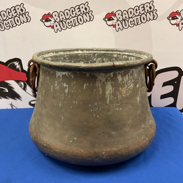 Large antique copper cauldron with iron handles, rustic kitchen decor.