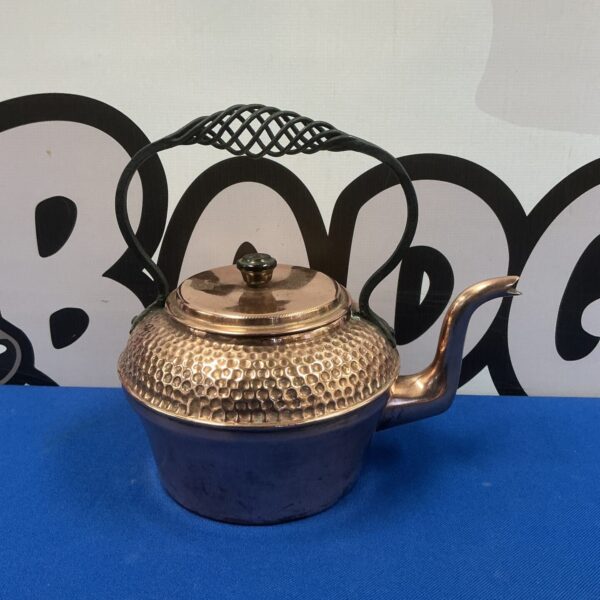 Antique copper kettle with iron handle and hammered texture.