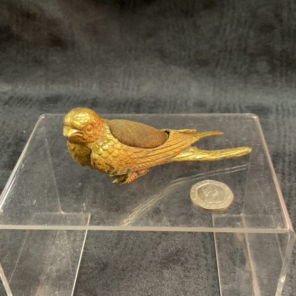 Antique gilt bronze bird pincushion on display.