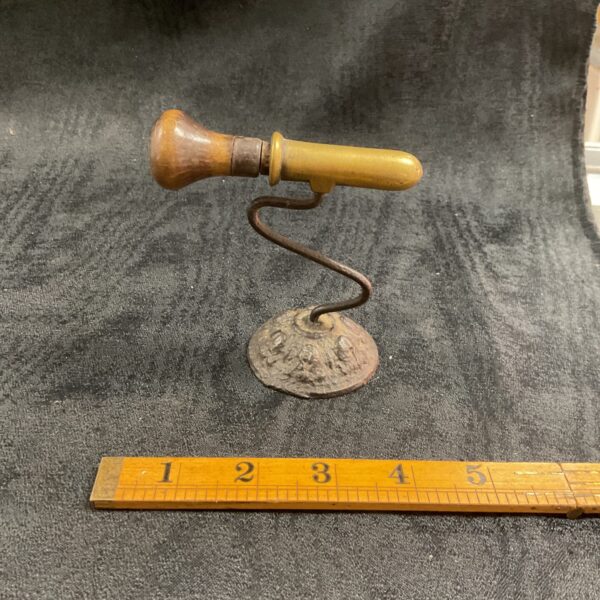 Antique goffering iron with brass construction and curved handle.