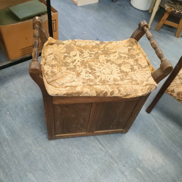 Antique piano stool with patterned upholstered seat and turned legs.
