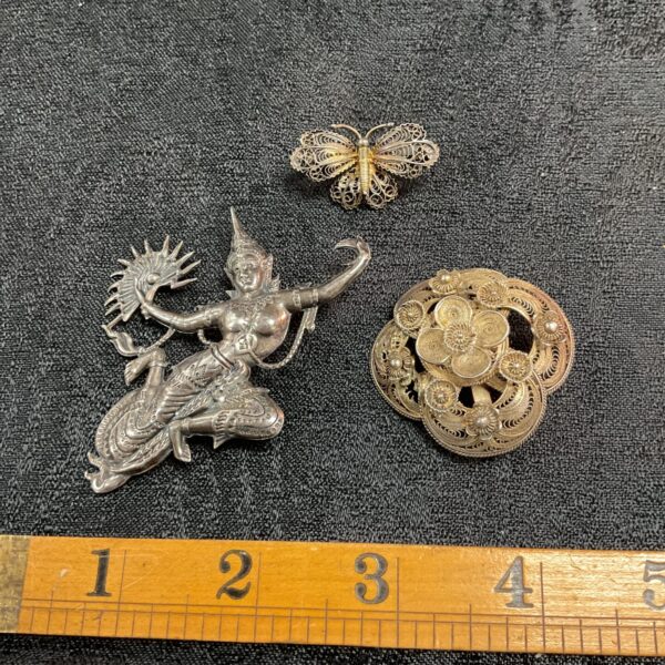 Antique silver brooches with delicate floral designs, vintage jewellery.