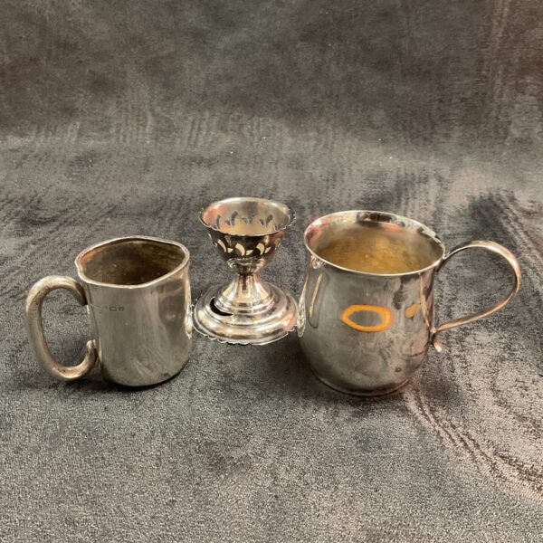 Antique silver plate and silver jug set displayed on a textured background.