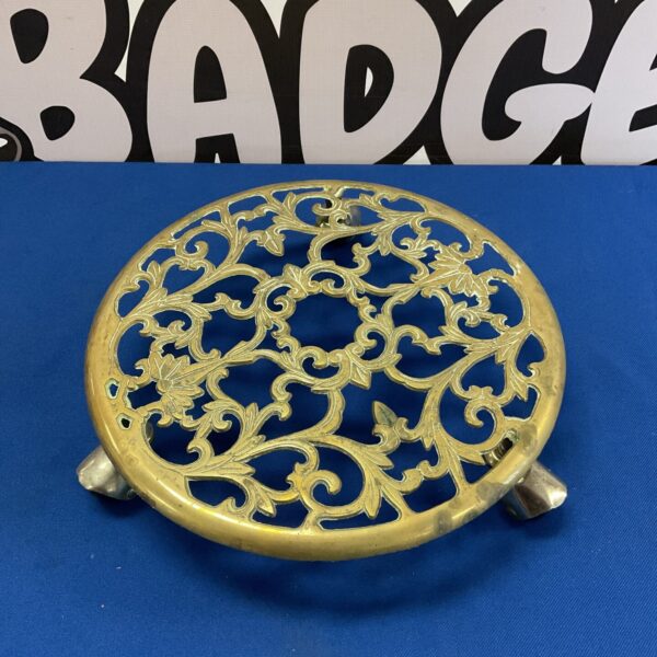 Intricate Art Nouveau brass trivet with floral design on castors.