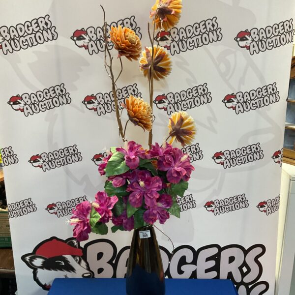 Vibrant artificial flower arrangement in a bronze effect vase.