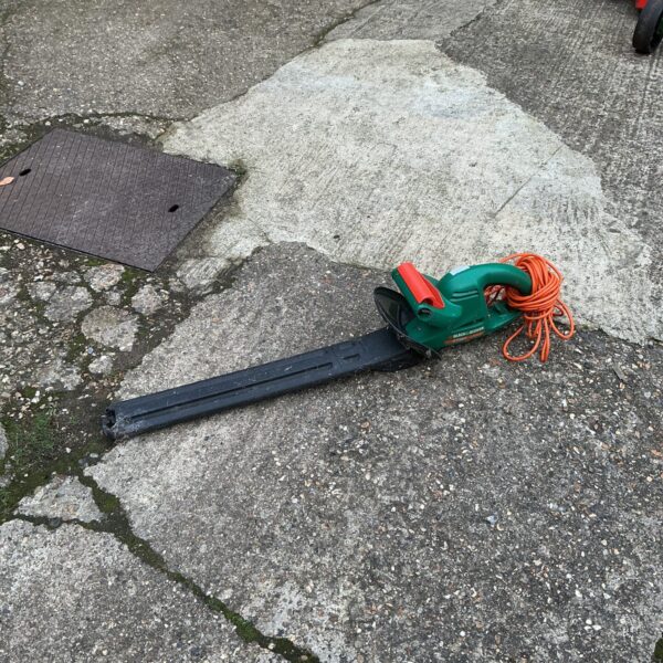 Used Black and Decker electric hedge trimmer for garden landscaping.