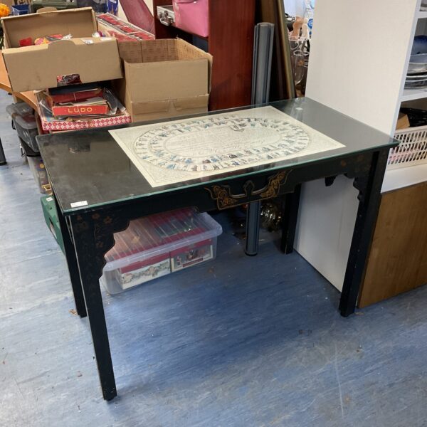 Black lacquered desk with gold accents and glass top.