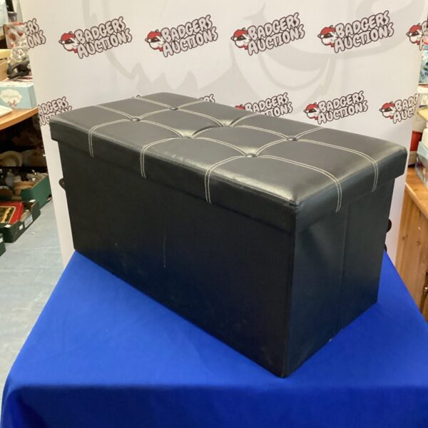 Black leather folding ottoman for seating and storage.