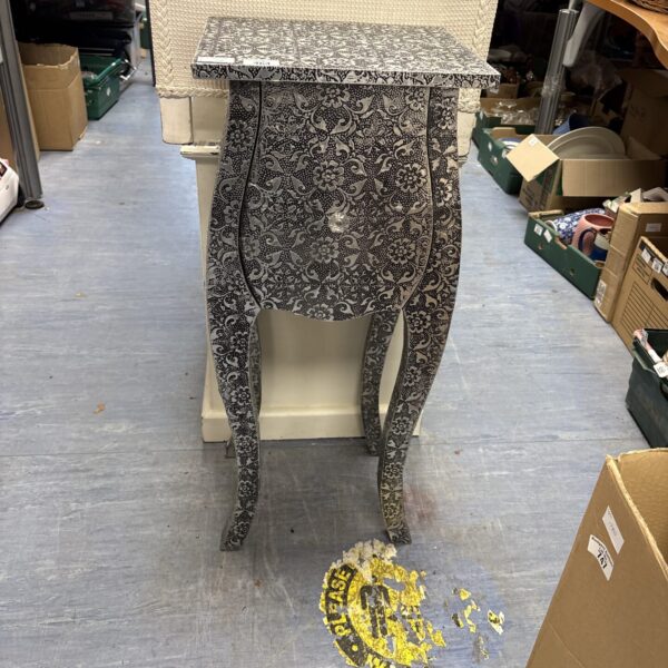 Intricate silver embossed blackened metal bedside cabinet.