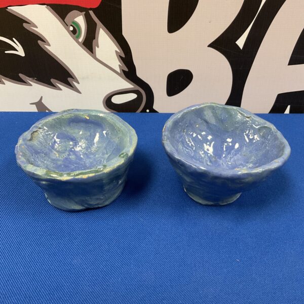 Pair of blue glazed studio pottery bowls on blue surface.
