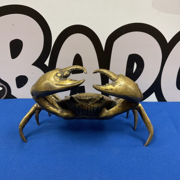 Detailed brass crab sculpture on blue surface.