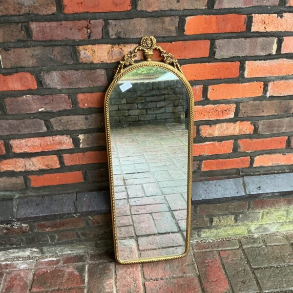 Ornate brass hall mirror with detailed frame.