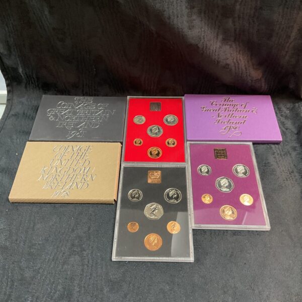 British coin proof sets from 1978, 1980, and 1981 displayed on a surface.