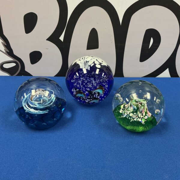 Lot of three Caithness glass paperweights with colourful designs.