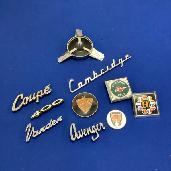 Vintage car badges lot featuring Rover, Coupe, and Avenger emblems.