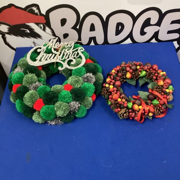 Two Christmas wreaths, one pom-pom and one pinecone, for festive holiday decor.