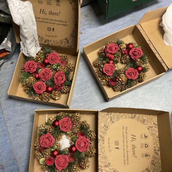 Three handmade Christmas wreaths with red roses for festive decor.