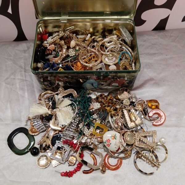 Tin filled with a diverse collection of vintage costume jewellery.