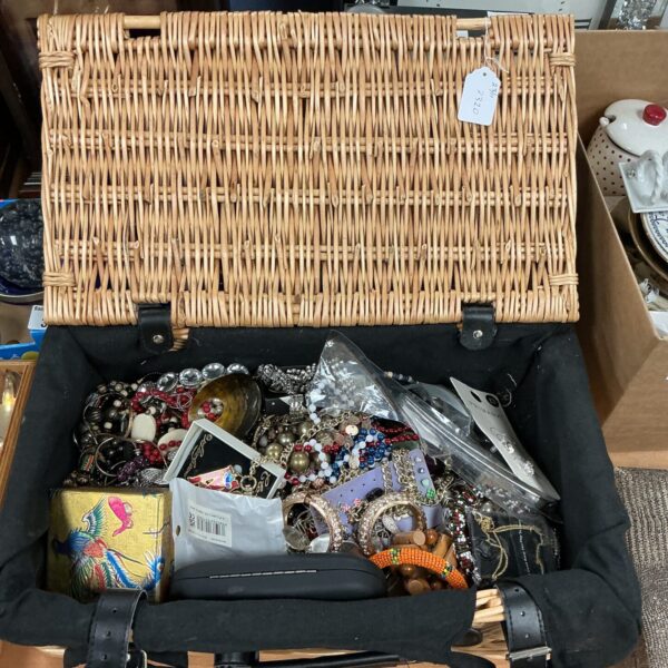 Wicker basket overflowing with colourful costume jewellery pieces.