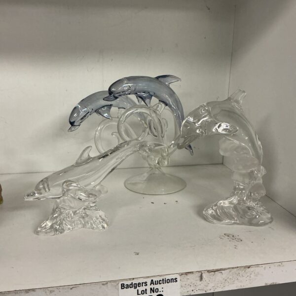 Three clear crystal dolphins, including a Lennox piece, on display.