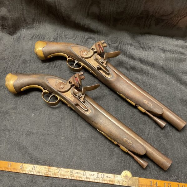 Pair of decorative flintlock pistols mounted on a wall.