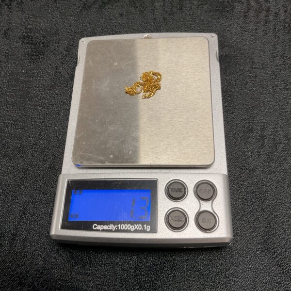 Digital pocket scale displaying 1.3g of gold scrap.