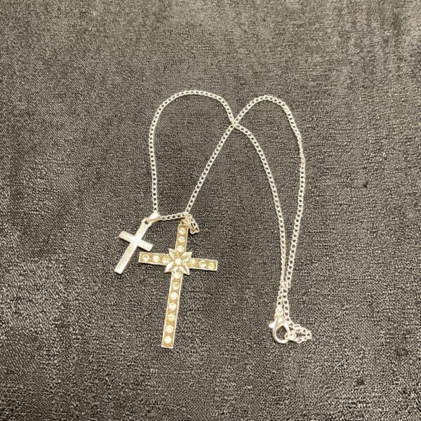 Close-up of a gold and silver tone double crucifix necklace pendant.