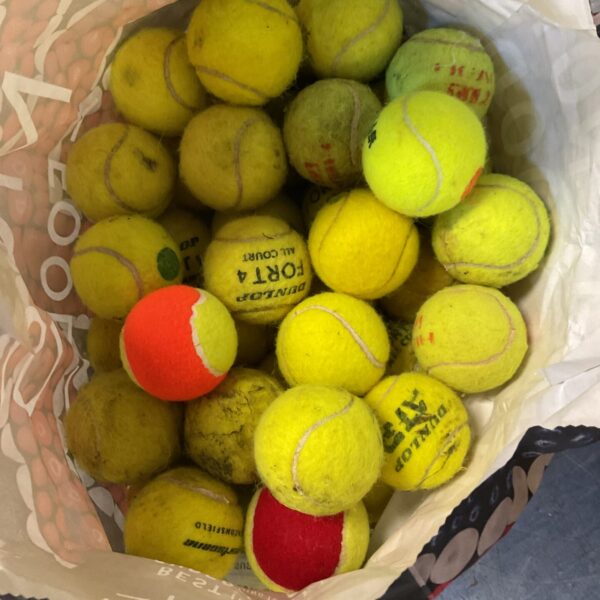 A lot of used Dunlop tennis balls in a bag.