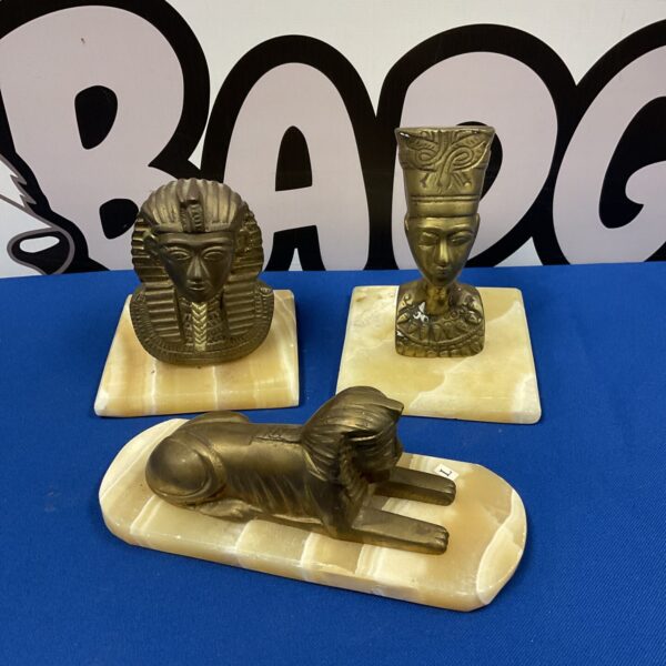 Vintage Egyptian brass busts of Tutankhamun, Nefertiti, and a sphinx on marble bases.