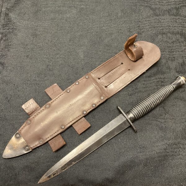 WWII Fairbairn Sykes fighting knife with leather scabbard, military collectible.