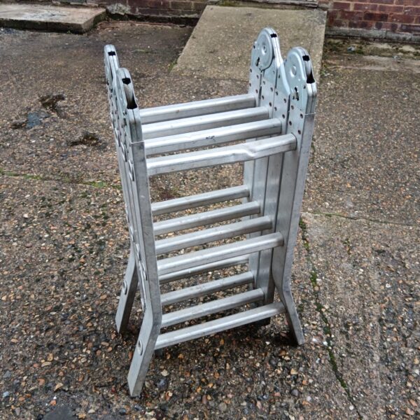 Silver folding aluminium ladder leaning against a wall.