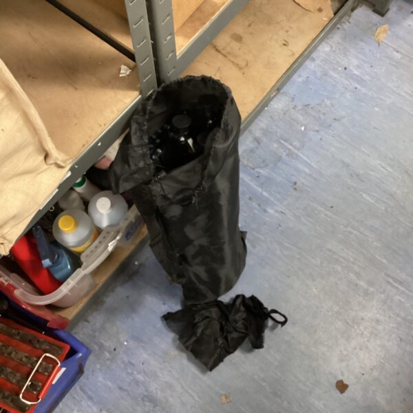 Black carry bag containing a folded camping table.