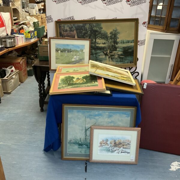 Large collection of framed prints and artwork displayed on a floor.