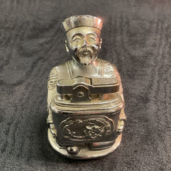 Vintage Fu Manchu novelty petrol table lighter, detailed sculpting.