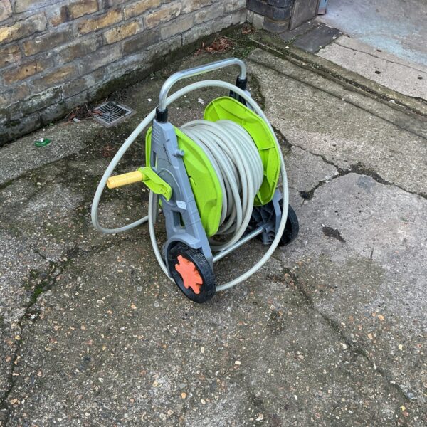Blue and green garden hose reel in an outdoor setting.