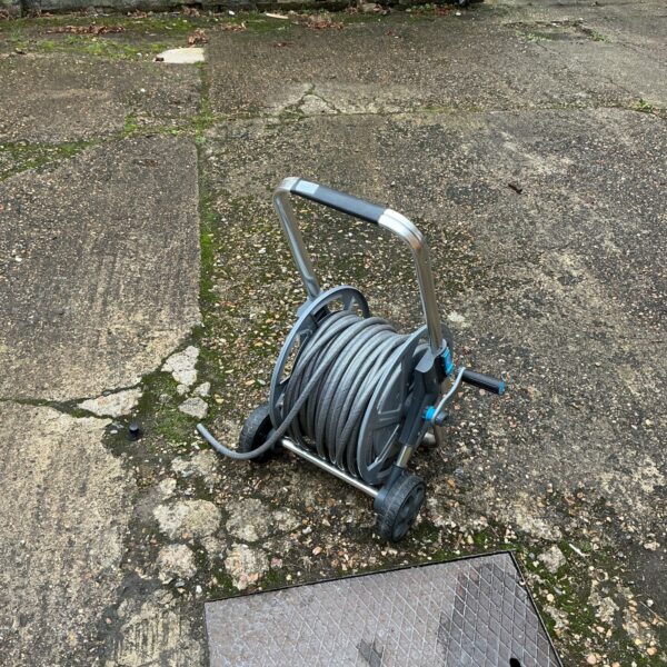 Used garden hose reel in an outdoor setting.