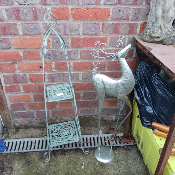 Metal garden pot stand and deer ornament for outdoor display.