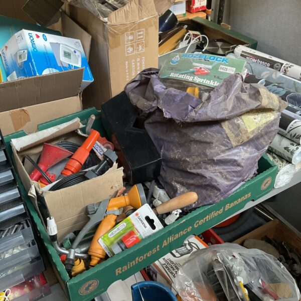 Box of garden items including a sprinkler kit and hose attachments.