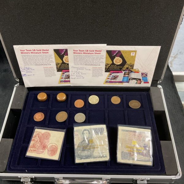 Open metal case displaying Team GB gold medal miniature sheets and coins.