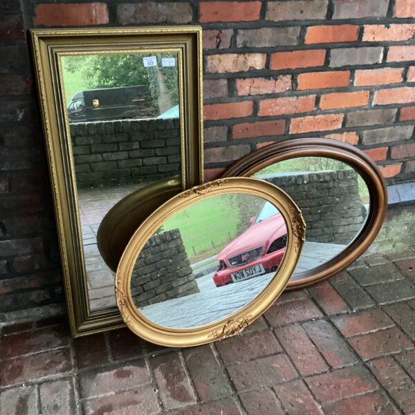 Lot of three gilt framed oval mirrors for wall decoration.