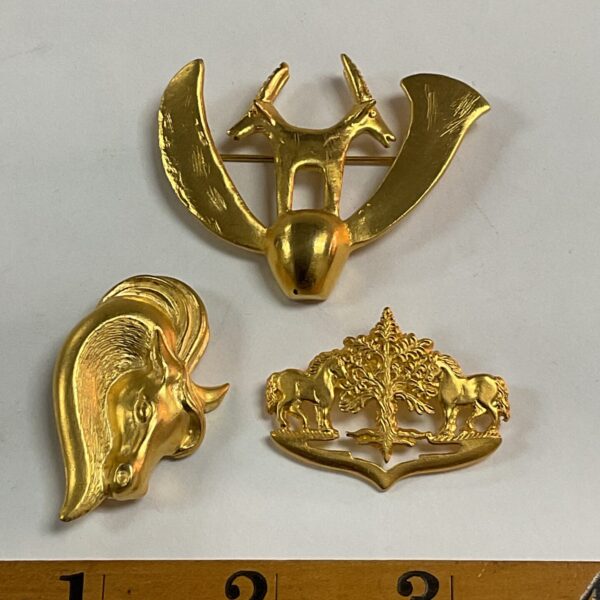 Vintage gilt metal brooch featuring a detailed horse head design.