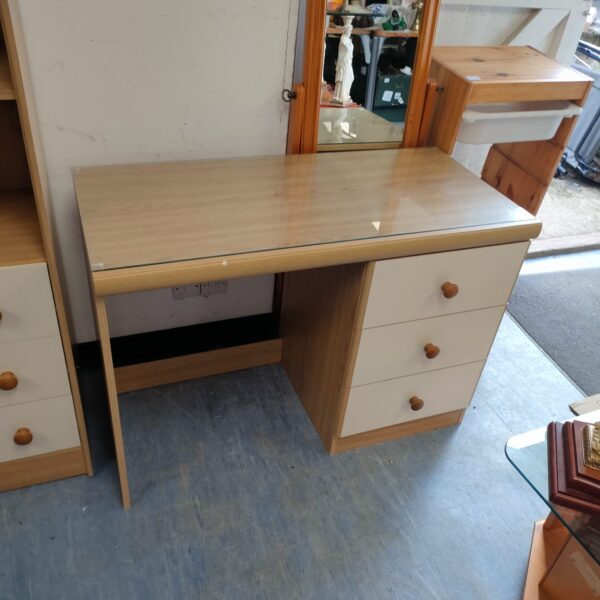 Vintage glass top desk with three drawers for home office use.