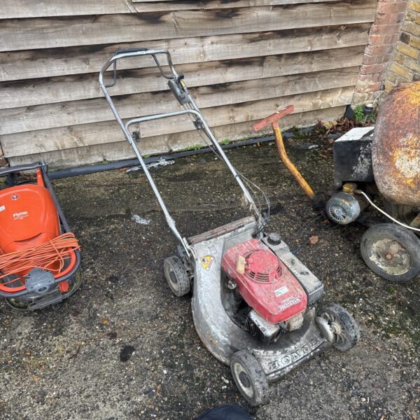 Side view of a vintage Honda HR216 petrol lawnmower in a garden setting.