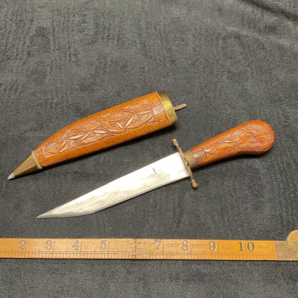 Vintage Indian carved knife with detailed wooden handle and sheath.
