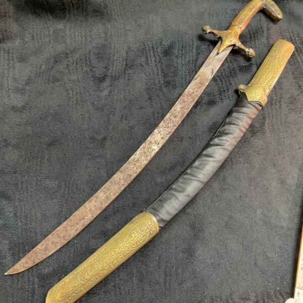 Vintage Islamic Arab ceremonial sword with curved blade and decorated hilt.