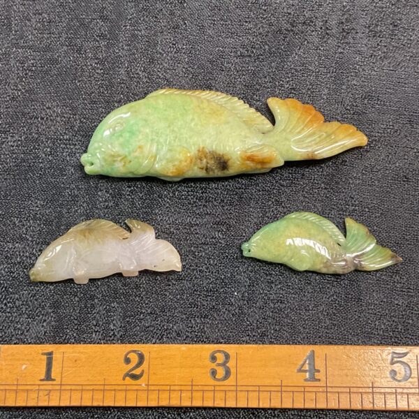 Pale green jade carving of three carp swimming together.