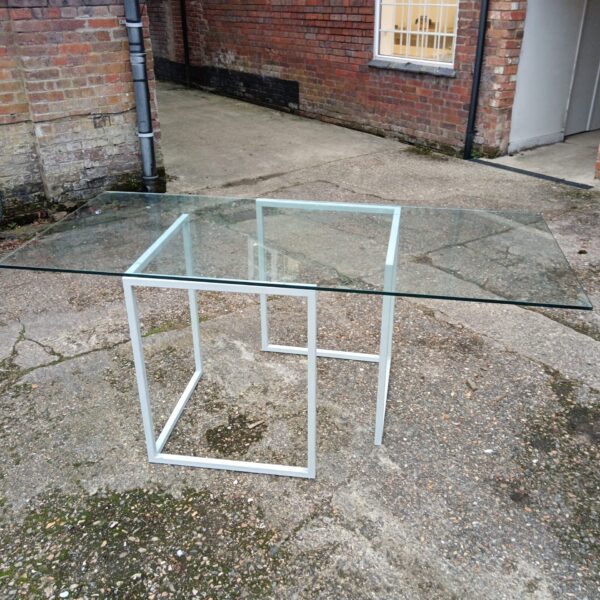 Large glass dining table with chrome frame in a modern setting.