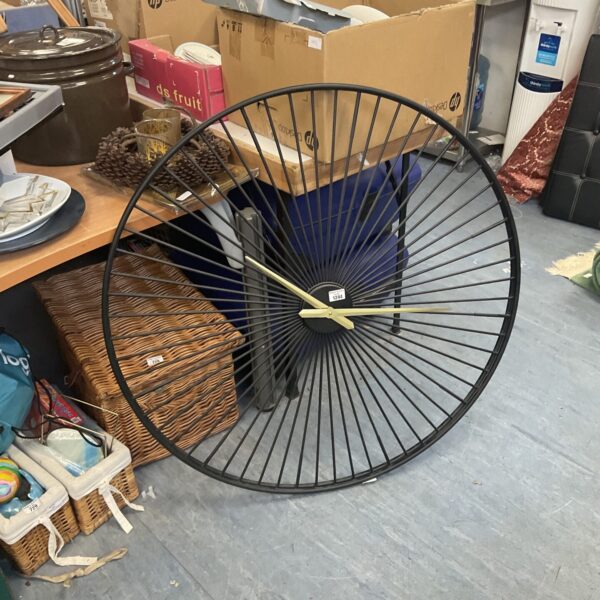 Large vintage quartz wall clock with metal wheel design.