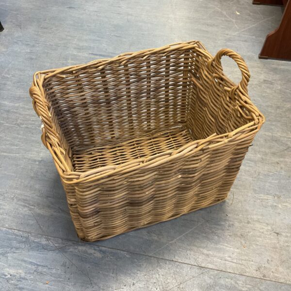 Large wicker log basket for firewood storage near a fireplace.
