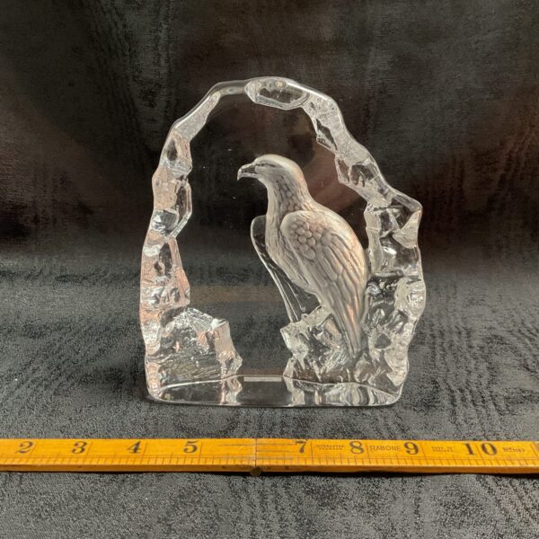 Front view of Mats Jonasson crystal eagle sculpture on a ruler.